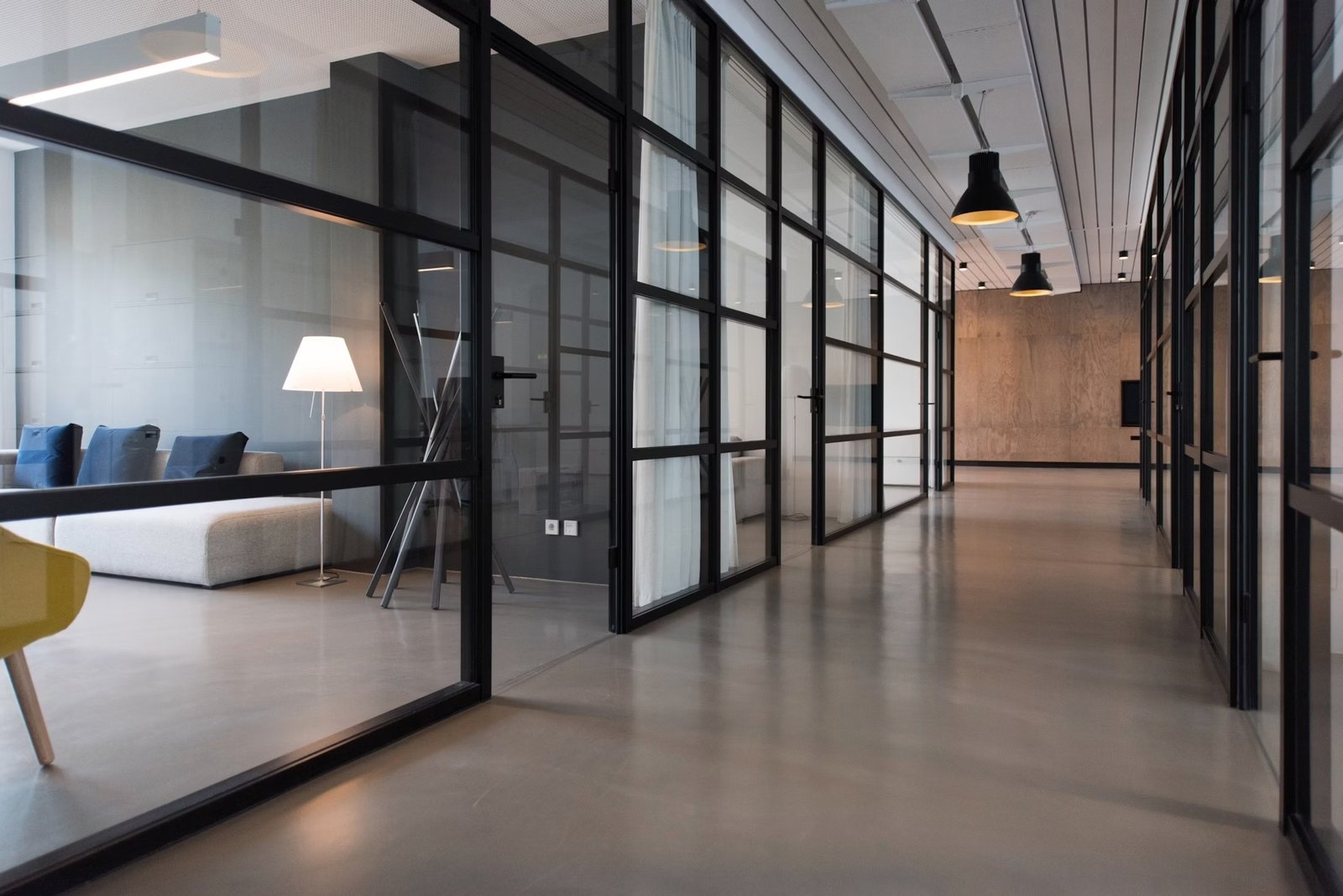 Light-filled office corridor with glass meeting-room partitions